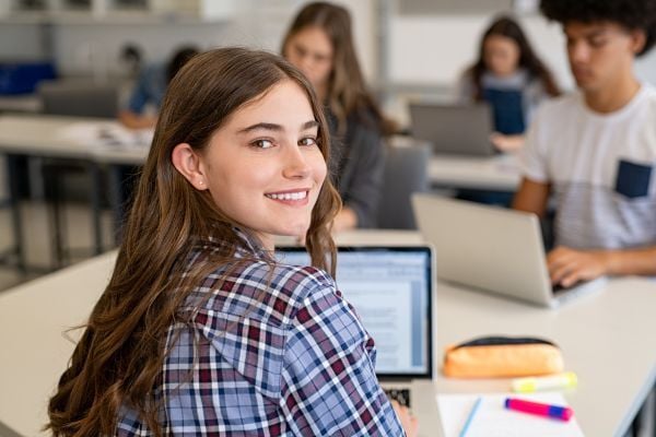 Student working at their laptop smiling