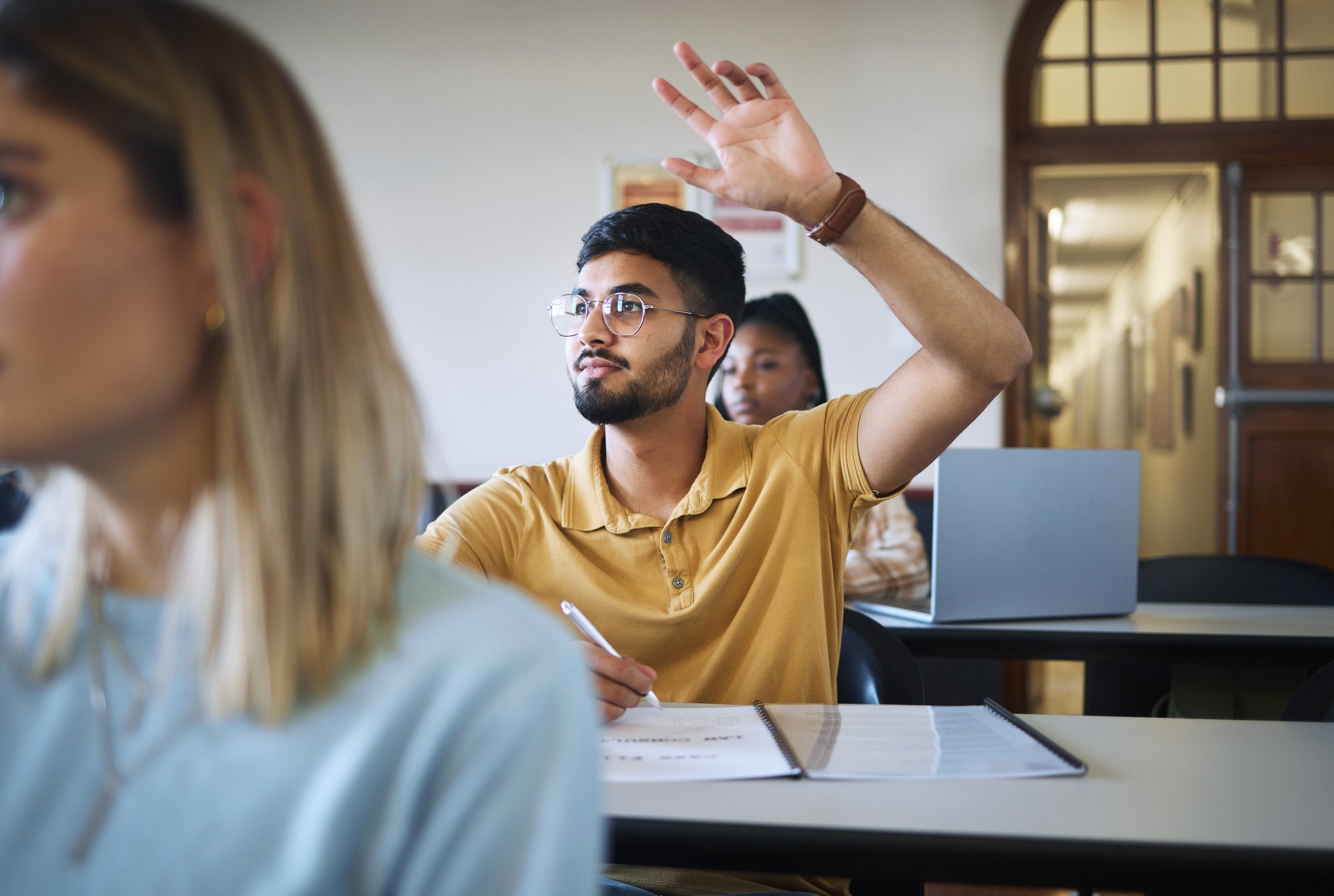 Student in class putting their hand up 